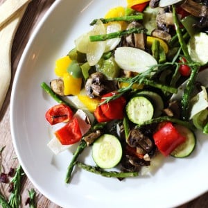 White platter containing oven roasted vegetable including asparagus, zucchini, squash, green peppers and onions.