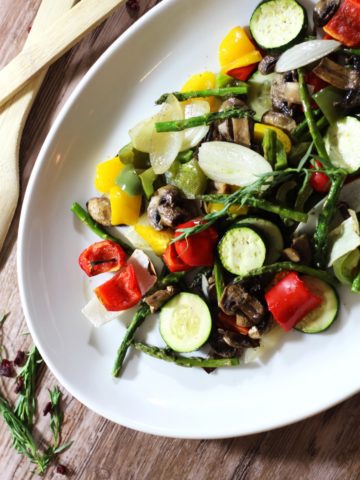 White platter containing oven roasted vegetable including asparagus, zucchini, squash, green peppers and onions.