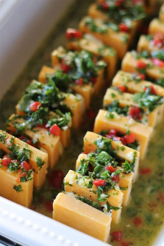 Appetizer of sharp cheddar cheese and cream cheese marinated and topped with parsley, pimentos, olive oil and garlic.