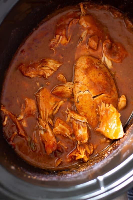 Cooked chicken breasts in a crockpot with a salsa based sauce.