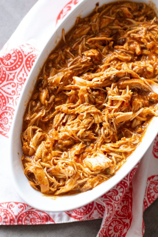 White bowl containing shredded chicken cooked in salsa.