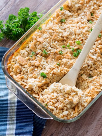 Glass Pyrex dish containing a hearty Chicken and Rice Casserole topped with parsley, serving spoon in casserole.
