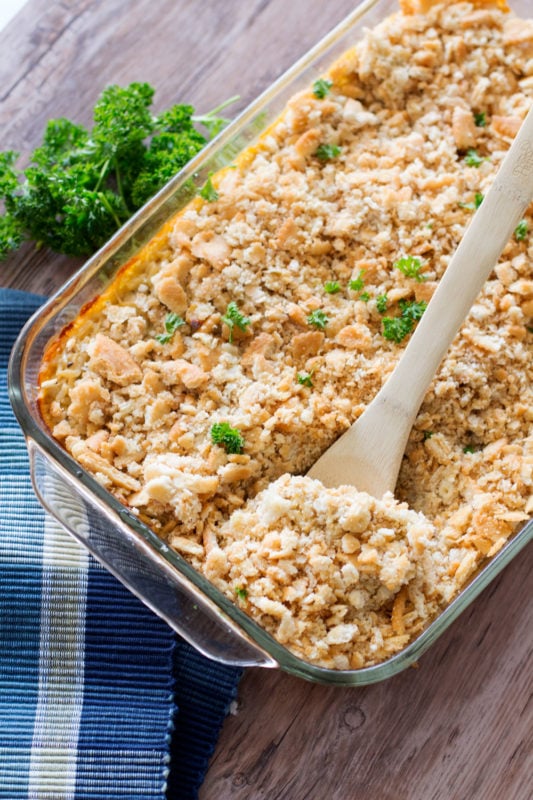  Chicken and Rice Casserole served in a glass casserole dish, white bowl of casserole on wooden table.