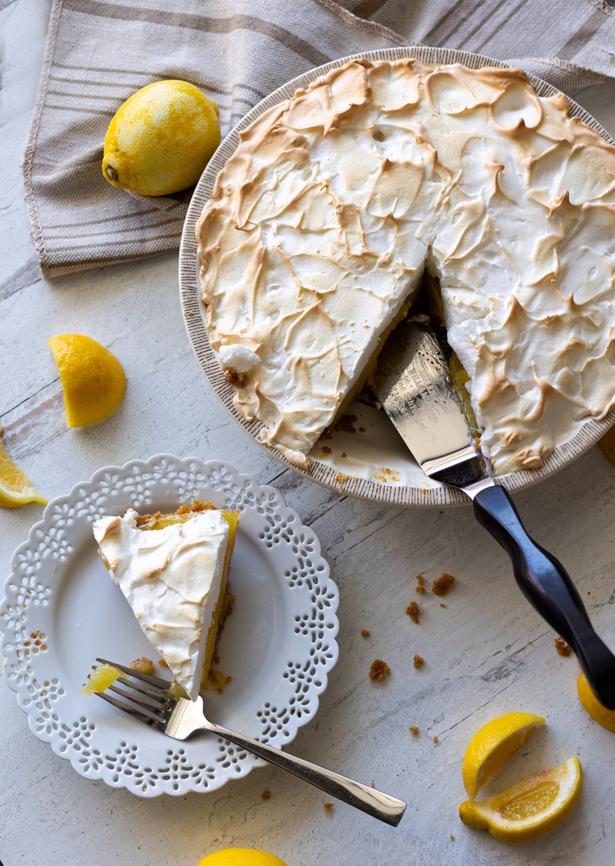 Person slicing and serving a piece of lemon meringue pie. 