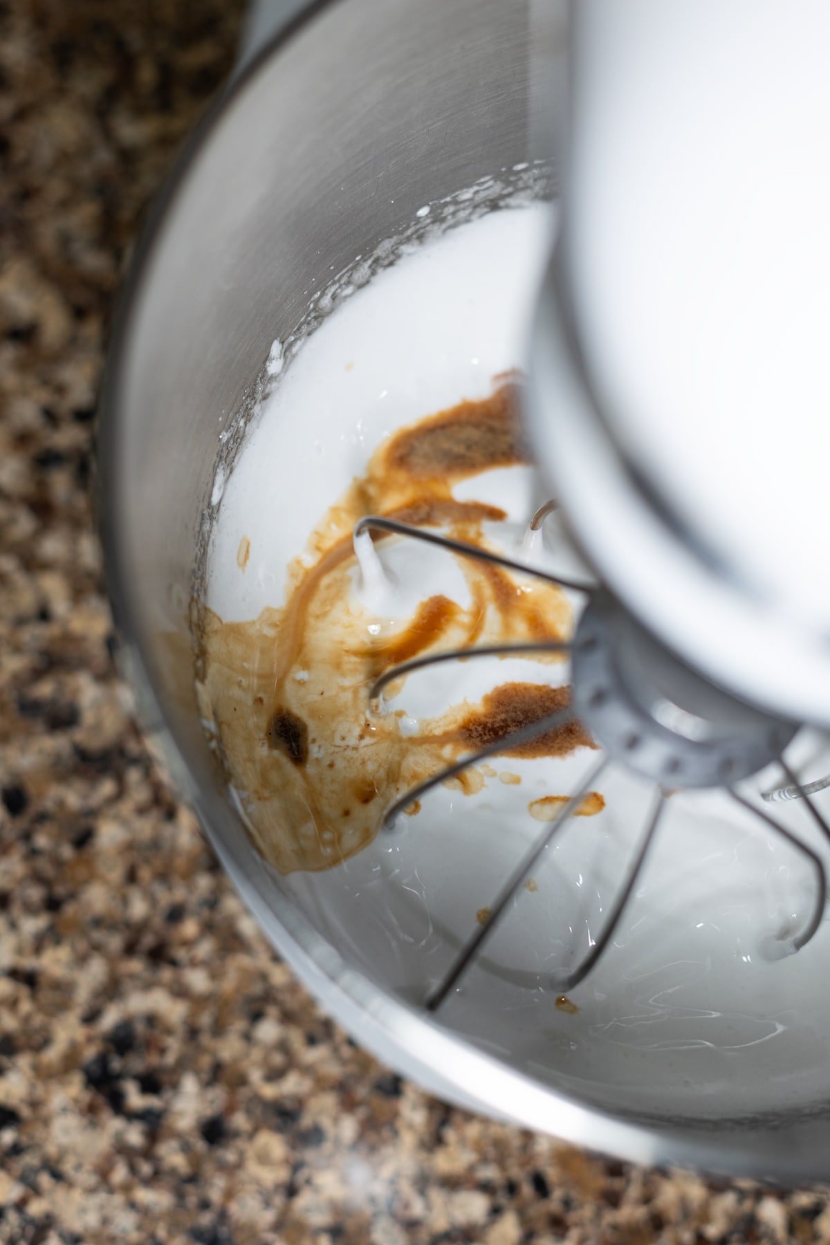 Person adding vanilla extract to homemade meringue.