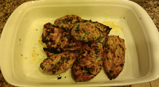 A pyrex dish of grilled chicken breasts seasoned with cilantro.