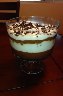 A close up of a large glass dessert dish of layers of tiramisu covered with mini chocolate chips.