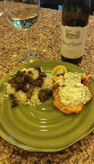 A plate with salmon covered in dill pepperoncini cream sauce with mushroom rice on a counter.