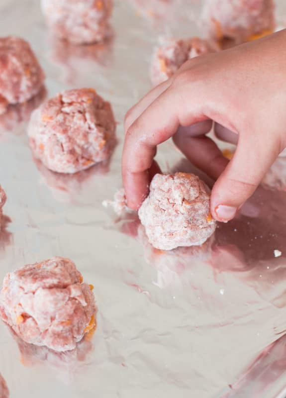 Person placing meat balls on cookie sheet.