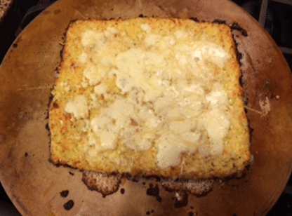 The cheesy garlic cauliflower breadsticks rolled out on the cooking stone after baking.