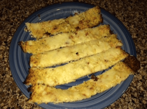 The cheesy garlic cauliflower breadsticks cut into five breadsticks on a blue plate.