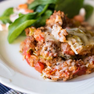 White plate containing Cabbage Roll Casserole served with a spinach salad.