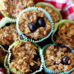 Brown bowl with a red and white checkered napkin containing 7 Baked Oatmeal Blueberry Oatmeal Cupcakes.