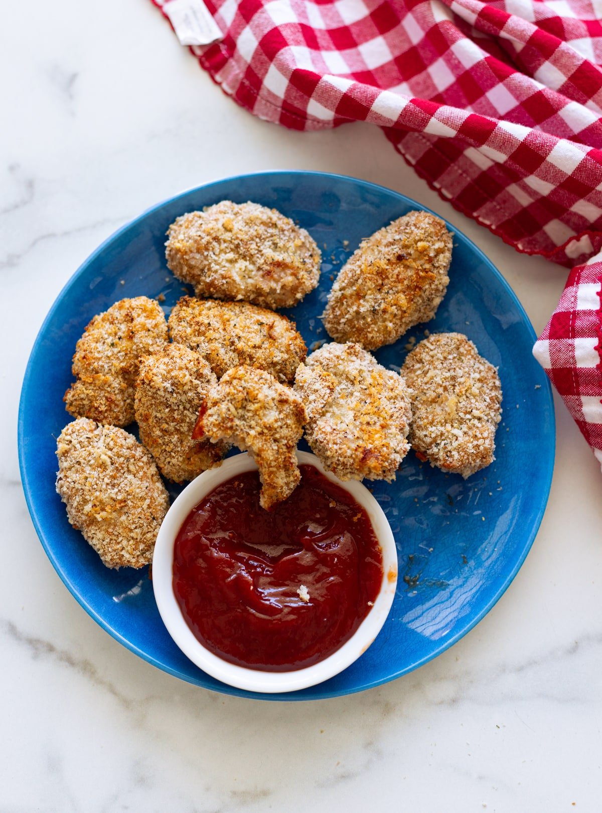 Blue plate filled with baked turkey tots and ketchup.