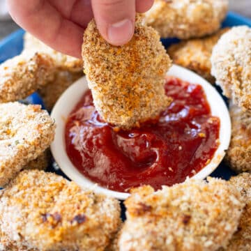 Person dipping a turkey nuggets into ketchup.