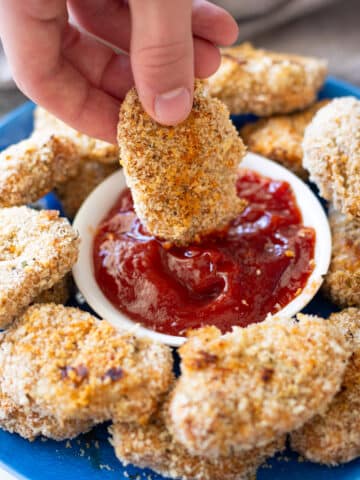 Person dipping a turkey nuggets into ketchup.