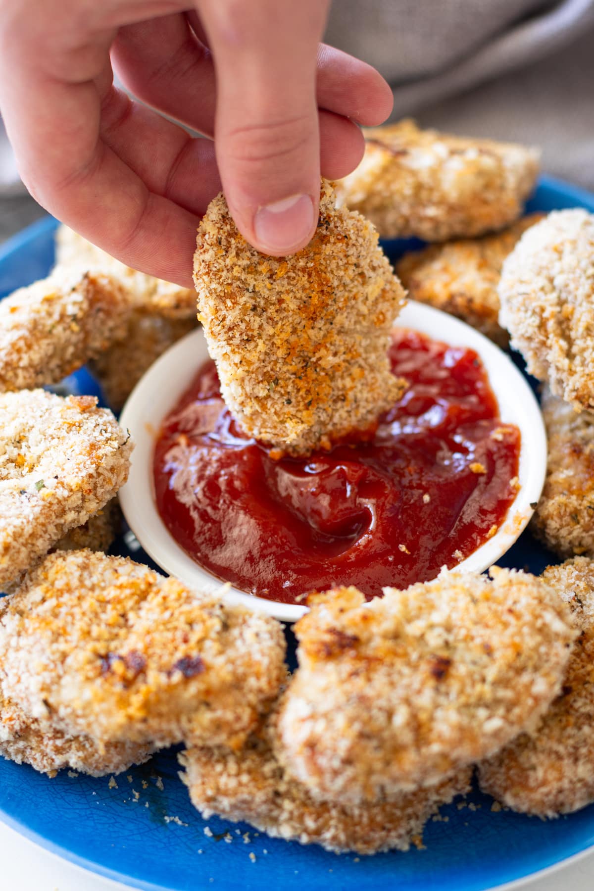 Person dipping a turkey nuggets into ketchup.