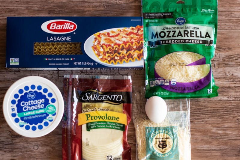 Ingredients for making lasagna, lasagne noodles, mozzarella cheese, cottage cheese, provolone cheese, egg and Parmesan cheese.