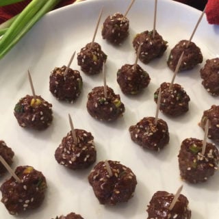 Even rows of Asian Teriyaki Meatballs with toothpicks on a white plate
