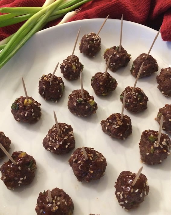 Even rows of Asian Teriyaki Meatballs with toothpicks on a white plate