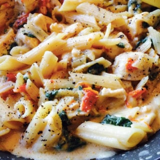 Blue plate containing Chicken Florentine with Sun Dried Tomato Pasta topped with fresh ground pepper.
