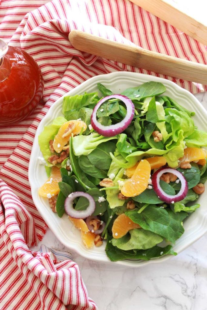 A green salad topped with candied pecans, diced apples, and goat cheese crumbles.