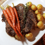 A large dish filled with pot roast and carrots and potatoes.