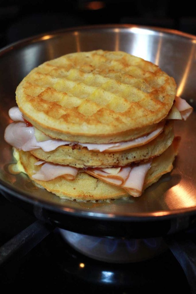 A Monte Cristo Sandwich made with turkey, cheese and waffles being toasted in a skillet.