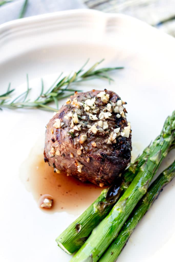 Grilled filet mignon topped with chopped garlic and rosemary, served with asparagus.