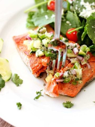 Pan Seared Salmon topped with a cucumber lime salsa, fork in salmon.