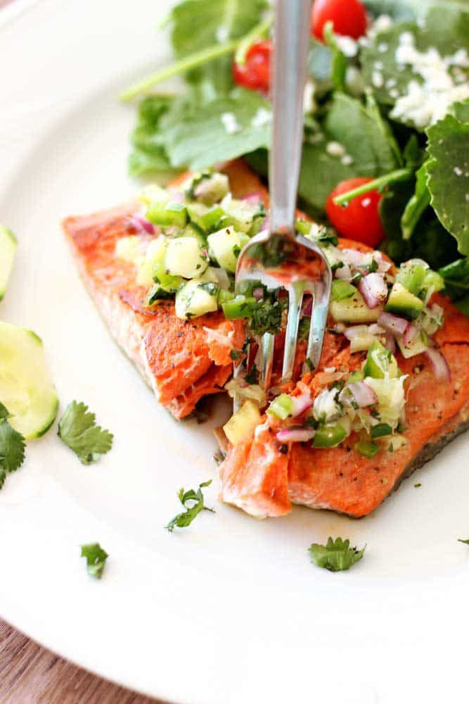 Pan-Seared Salmon topped with a cucumber lime salsa, fork in salmon.