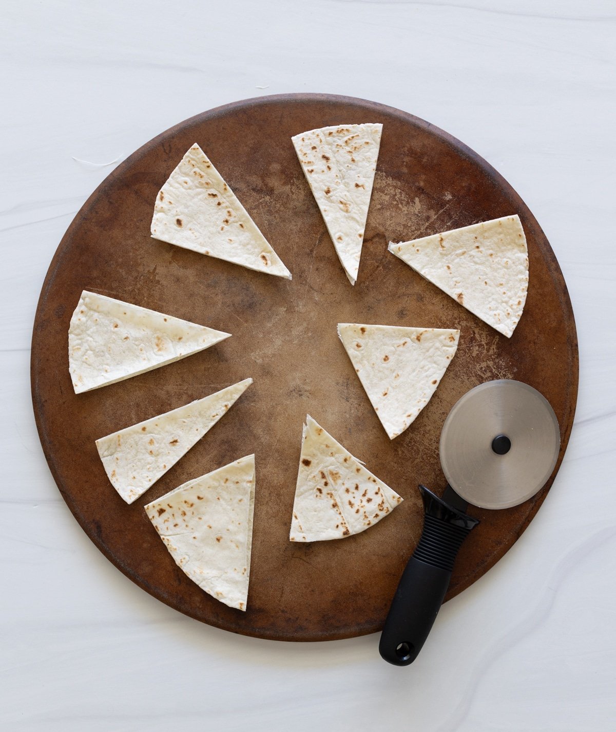 Person using a pizza cutter to make baked chips. 