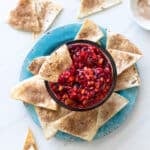 Bowl filled with fruit salsa and cinnamon chips being served alongside.