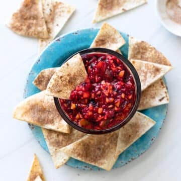Bowl filled with fruit salsa and cinnamon chips being served alongside.