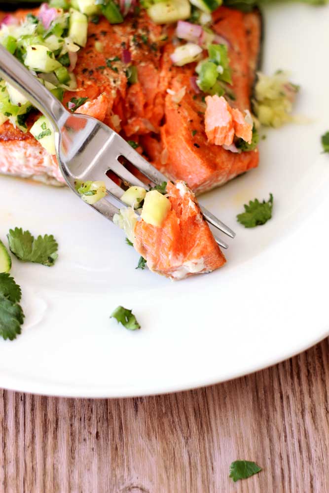 A fork containing fresh Pan-Seared Salmon topped with cilantro lime salsa.