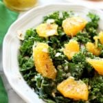 A close up of an orange and kale salad on a white plate