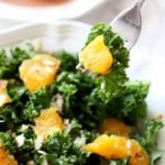 A plate of orange and kale salad on a fork