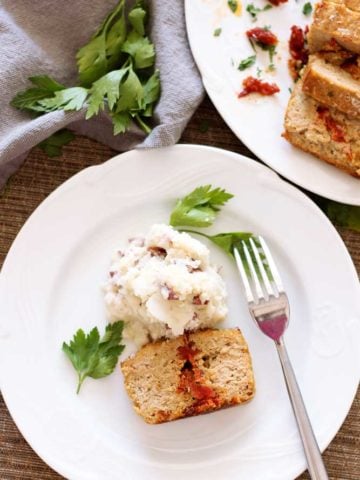 White plate containing Feta and Sun-Dried Tomato Meatloaf with mashed potatoes.