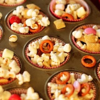 Cupcake tin filled with a popcorn snack containing popcorn, pretzels and M&Ms.