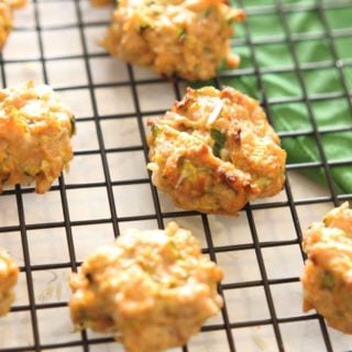 7 Chicken Zucchini Bites sitting on a black wire cooling rack, green napkin on table.