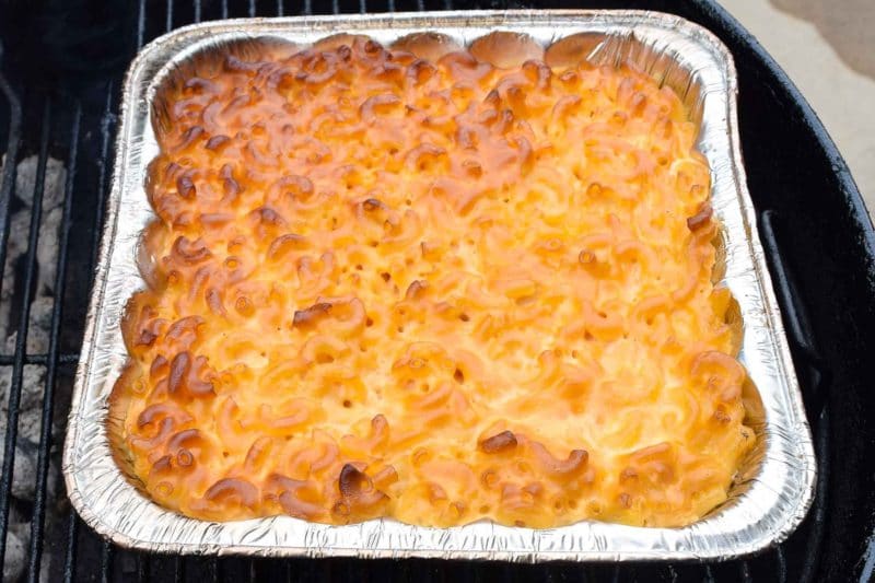 Aluminum pan containing Smoked Mac and Cheese, sitting on a grill.