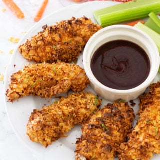 White plate containing 5 air fried chicken tenders, BBQ sauce on side.