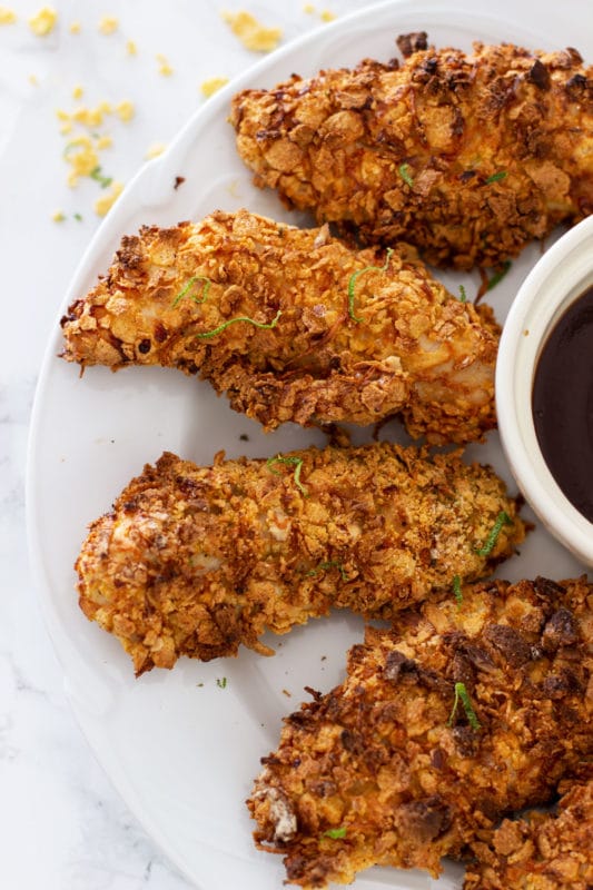 White plate containing 5 air fried chicken tenders, BBQ sauce on side.