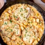 Pan seared apple smothered pork chops in a cast iron skillet.