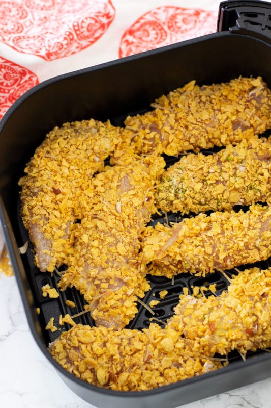 Breaded gluten free chicken tenders in an air fryer pan.