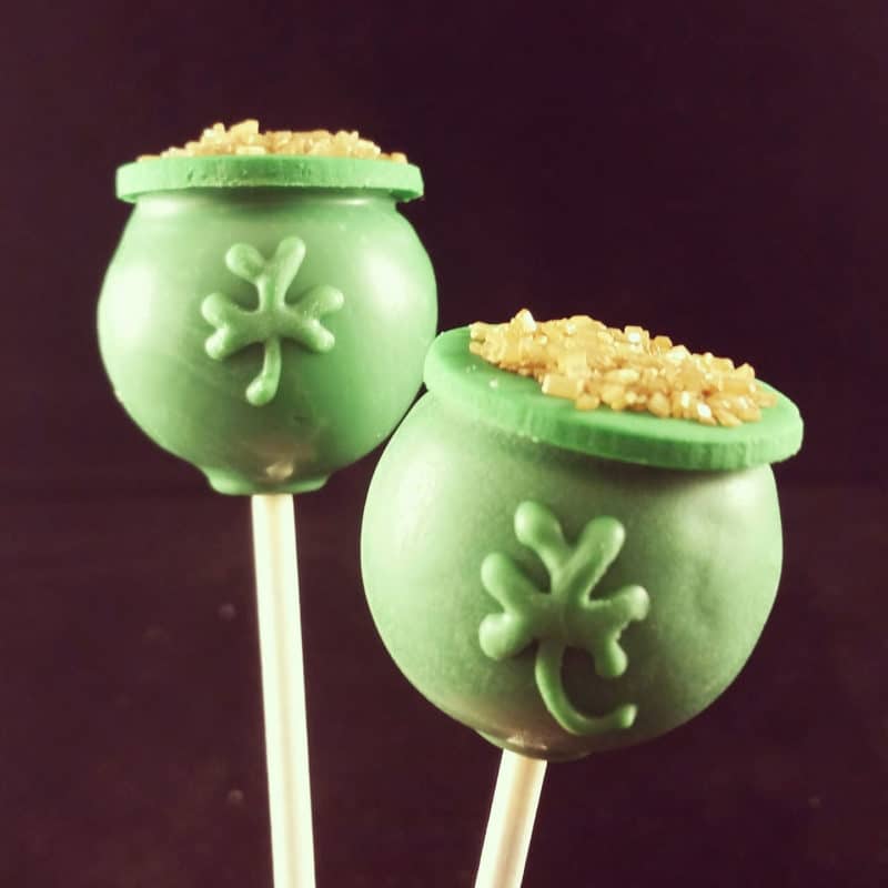 2 green pots of gold St. Patrick's Day Cake pops topped with gold glitter.