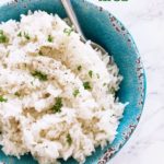 Blue bowl containing white rice made in the instant pot topped with pepper and fresh parsley.