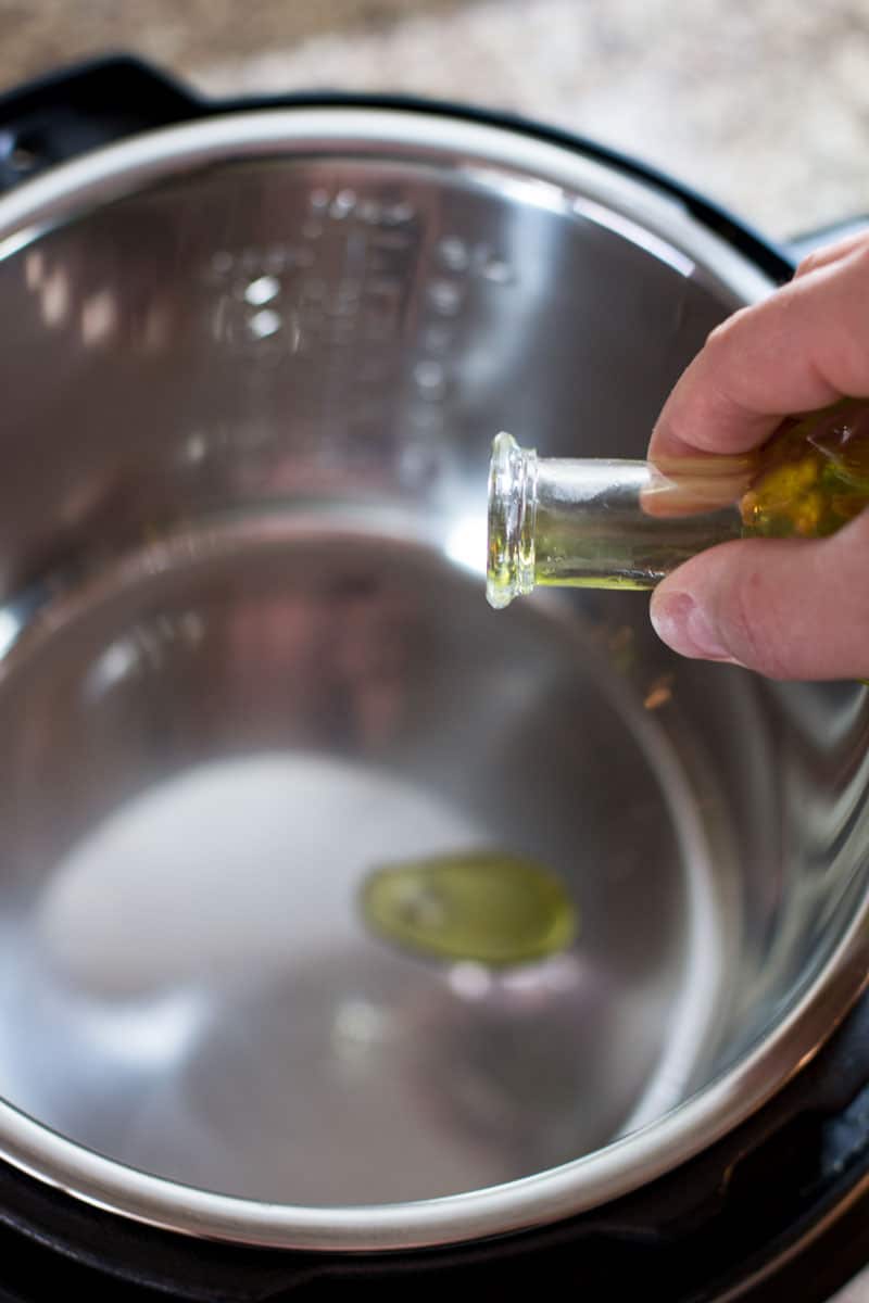 Pouring olive oil into an instant pot.