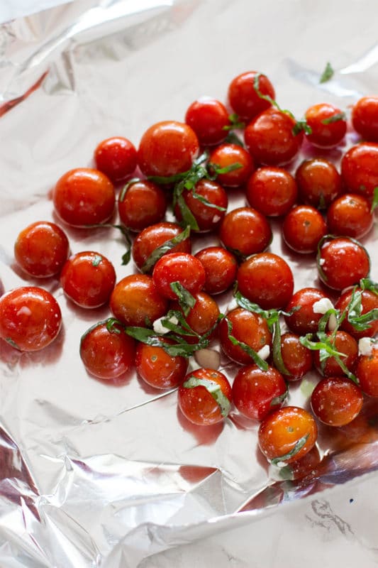 20 cherry tomatoes in marinade spread on piece of aluminum foil.