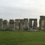 A stone building that has grass in front of the large rocks at Stonehenge.